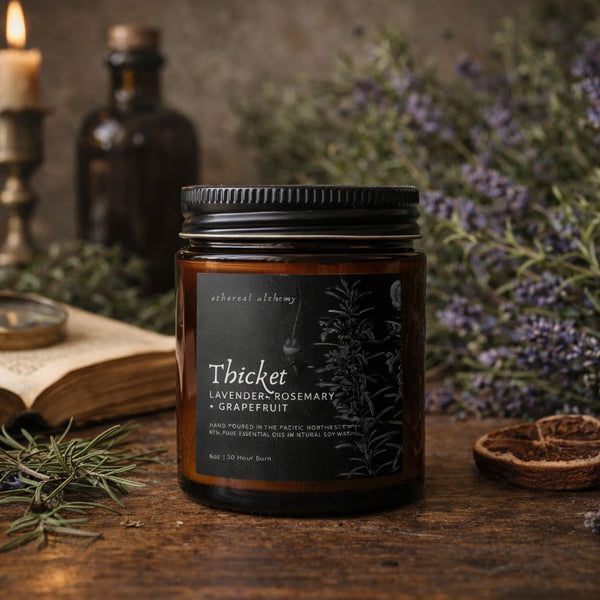 Candle jar labeled 'Thicket' with lavender and an open book on a wooden surface.